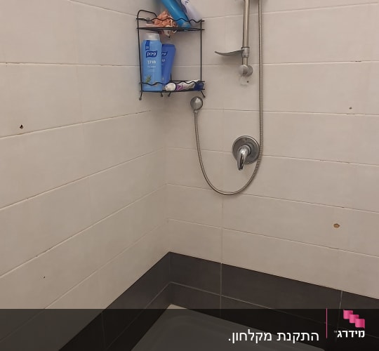 מקלחת עם ראש מקלחת ומדף עם מוצרי רחצה